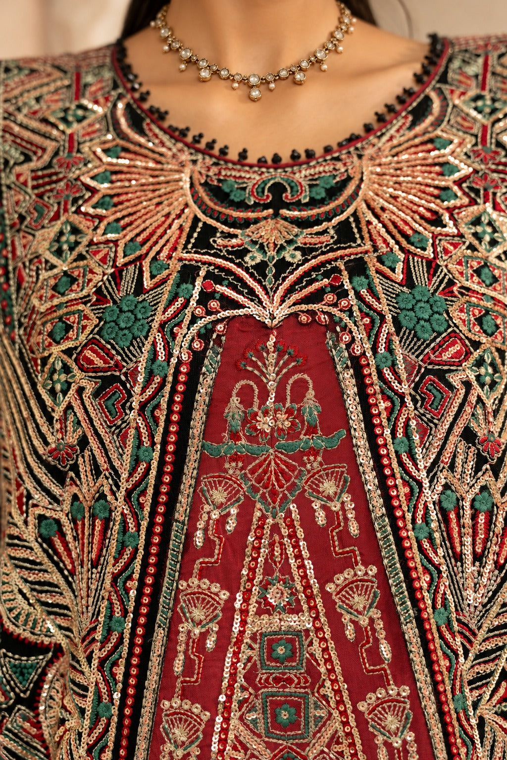 Black Onyx neckline embroidery close up, gold and crimson thread work